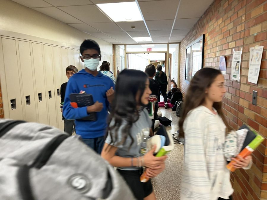 Glass hallway full of students during lunch period.