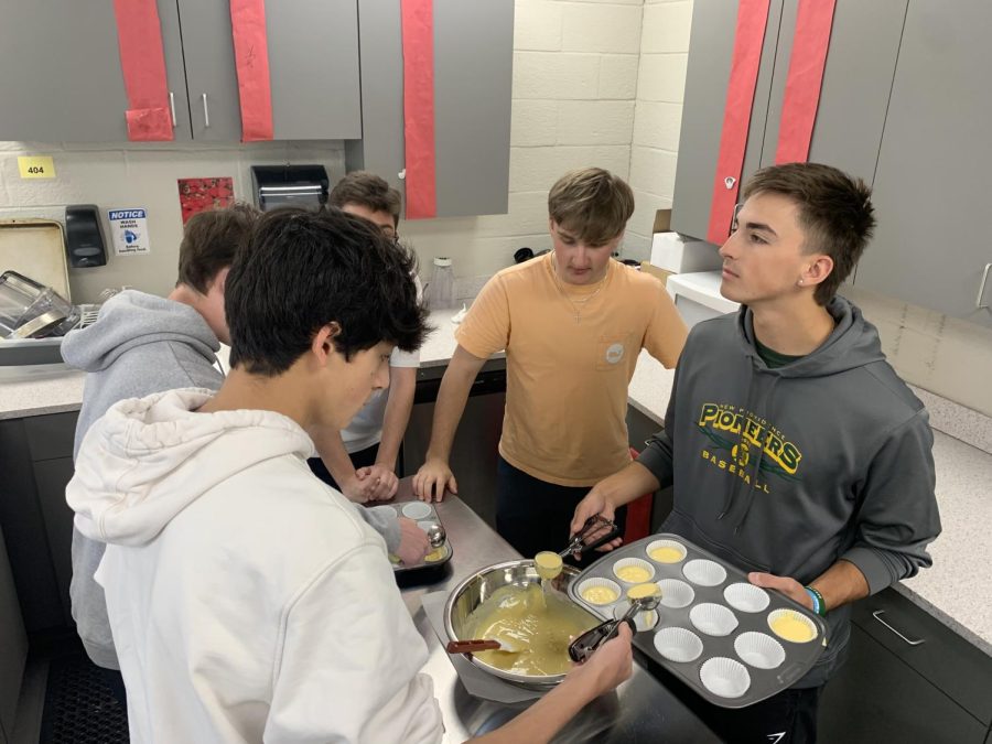 Students pour batter into the cupcake wrappers before they go into the oven. 