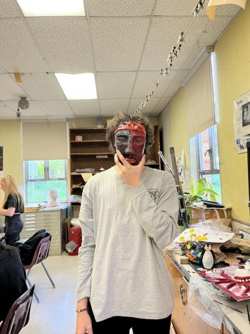 Senior John, is holding up his sculpted face he made using clay. 